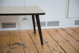 Vintage Mid Century coffee table corner, light top, dark tapered legs with brass caps.