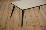 Vintage mid century coffee table's dark tapered legs, brass caps, and light tabletop edge.