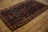 Full angled view of an antique Sarouk rug, showcasing its floral Tree of Life pattern on a deep indigo field.