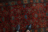 Overhead view showing the texture of the vintage Hamadan rug's red and blue Herati design.