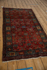 Angled view of the vintage Hamadan rug's crab-style border and ruby red Herati pattern.