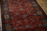 Angled view of a fine vintage Hamadan rug showing gem-like ruby and sapphire tones in the Herati pattern.
