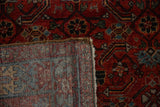 The hand-knotted foundation and low wool pile on the corner of a vintage Persian Hamadan rug.