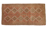 Vintage distressed Kurdish runner with geometric medallions in blush, dusty red, and green.