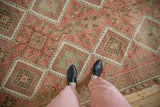 The even, time-softened wear on a Kurdish rug with blush and copper green geometric medallions.