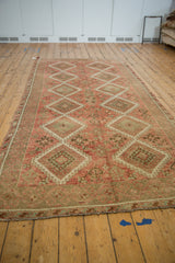 Full length angled view of a vintage Kurdish runner with a distressed geometric design.