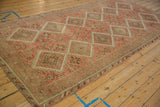 Angled view down the length of a vintage Kurdish runner with a geometric pattern of interconnected guls.