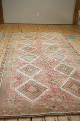 A long perspective view down the length of a distressed Kurdish runner in pale blush and silver.