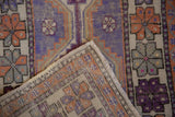 Aubergine and terracotta geometric pattern of a distressed Oushak rug, showing hand-knotted foundation.