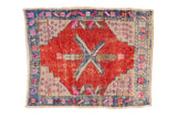 Distressed Oushak square mat, geometric starburst in red, blue, ivory, and pink.
