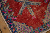 Distressed Oushak rug corner, showing sapphire blue border and fuchsia seed motifs on worn pile.