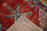Distressed cherry red Oushak rug front with wear and hand-knotted ivory foundation.