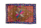 Distressed Oushak rug with an oversized magenta starburst, red patterned corners, and blue floral border.