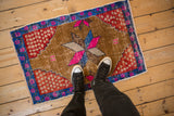 Distressed vintage Oushak mat with feet, showing worn ochre field and bold geometric starburst.