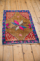 Angled view of vintage distressed Oushak rug, highlighting worn texture and bright magenta blossoms.