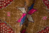 Distressed texture of vintage Oushak rug with magenta, blue starburst, red spandrel.