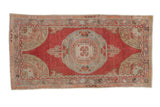 A vintage distressed Oushak rug runner with a raspberry red field and a slate blue central medallion.