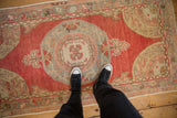 Top-down view of a vintage Oushak runner showing its scale, distressed texture, and red and slate blue colors.