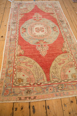 Angled view of a vintage Oushak runner with a raspberry red field, central medallion, and softly distressed patina.