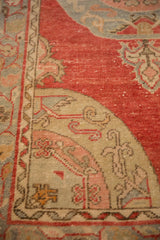 Worn hand-knotted texture on the corner spandrel of a vintage Oushak in raspberry and slate blue.