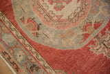 Close-up of the distressed Oushak rug's worn pile, showing corner details in slate blue and dusty raspberry red.