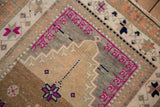 Distressed Oushak rug close-up: magenta stepped pattern with starburst motifs.