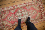 Overhead view of a person standing on a distressed Oushak rug runner in red and ivory.