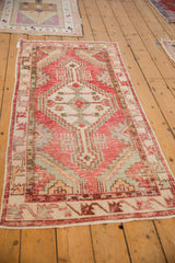 Angled view of a distressed Oushak runner showing its soft cherry red and sand geometric design.