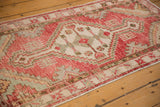 The meandering vine border and low-pile texture on a distressed vintage Oushak rug runner.