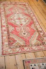 Vintage Oushak runner from a perspective angle, showing its distressed cherry red and sand tones.