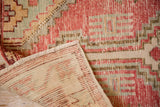 Folded corner reveals the hand-knotted foundation of a distressed vintage rug.