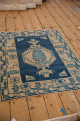 Distressed Oushak rug corner, highlighting the abrash field and geometric blue and beige border.