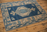 Corner detail of distressed Oushak rug, dusty sapphire and ivory geometric border, visible abrash.