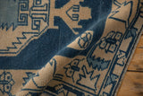 Distressed texture and serrated geometric pattern in dusty sapphire and ivory.