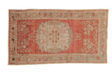 Distressed vintage Oushak rug with a large floral medallion in time-softened blush pink, ivory, and silver.