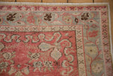 Intricate floral border in blush pink and silver on a low-pile distressed vintage Oushak rug.