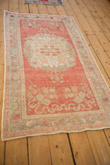 Perspective view of a distressed Turkish Oushak rug in soft blush pink, ivory, and silver tones.