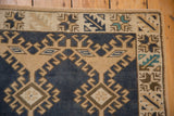 Distressed vintage Oushak rug: geometric hook and latch border in denim blue, ivory, beige, and teal.