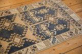 Distressed vintage Oushak rug edge showing dark denim blue and beige geometric patterns.