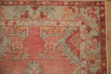 Distressed Oushak rug corner detail, revealing serrated palmettes in blush, seafoam, and soft wear.
