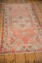 Distressed blush field of Oushak runner with pale seafoam spandrel, ruby red border.