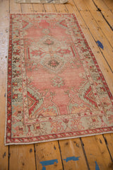 Distressed corner of the Oushak rug runner, highlighting blush, ruby, and seafoam geometric border motifs.
