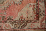 Geometric corner detail of a distressed Oushak rug in dusty blush, pale slate, and chocolate brown.