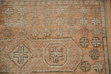 Distressed vintage Oushak rug pile texture with geometric motifs in warm sandalwood and beige tones.