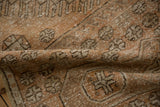 Distressed vintage Oushak runner's folded texture, featuring geometric motifs in sandalwood and pale coffee brown.