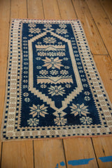 Angled view of a vintage Oushak rug with a cobalt blue and ivory geometric starburst pattern.