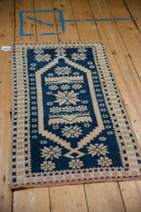 An angled perspective of the vintage Oushak rug's cobalt and sand geometric starburst pattern.