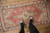 Distressed vintage Oushak runner with faded red abrashed field and ivory central floral medallion.