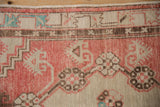 Distressed vintage Oushak rug detail, faded red field with worn knot heads and geometric patterns.