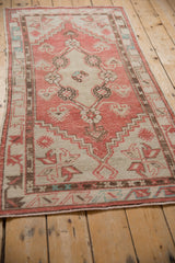 Vintage Oushak rug corner detail, featuring faded red, ivory, and seafoam geometric patterns.